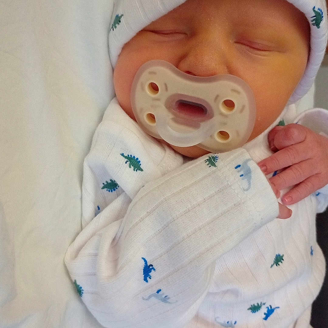 Maverick is registered to the contest to win money with this photo: architecture, baby, bed, blanket, bodypart, bonnet, building, cap, clothing, face, finger, furniture, glove, hand, hat, head, newborn, person, photography, portrait