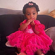 V'Niyah is registered to the contest to win money with this photo: toddler, child, pink_dress, curly_hair, hair_clip, shoes, couch, indoor, portrait, cute, baby, sitting, hand_in_mouth, home, furniture, soft_lighting, curiosity, young_child, casual, cozy