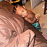 child, toddler, smiling, portrait, indoor, bedroom, bed, blanket, couch, carpet, braids, earring, shirtless, pants, playful, peeking, face, furniture, home, photography