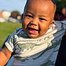 Ahlegend is registered to the contest to win money with this photo: baby, blurred_background, child, close_up, clothing, daylight, dinosaur, face, grass, greenery, happy, infant, laughing, outdoor, person, photography, portrait, smiling, sunlight, tongue_out