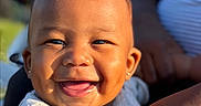 Ahlegend joined the competition — help win amazing prizes! adult, baby, child, close_up, clothing, earrings, eyes, face, hair, holding, infant, laughing, onesie, outdoor, parent, portrait, smiling, sunlight, teeth, topknot