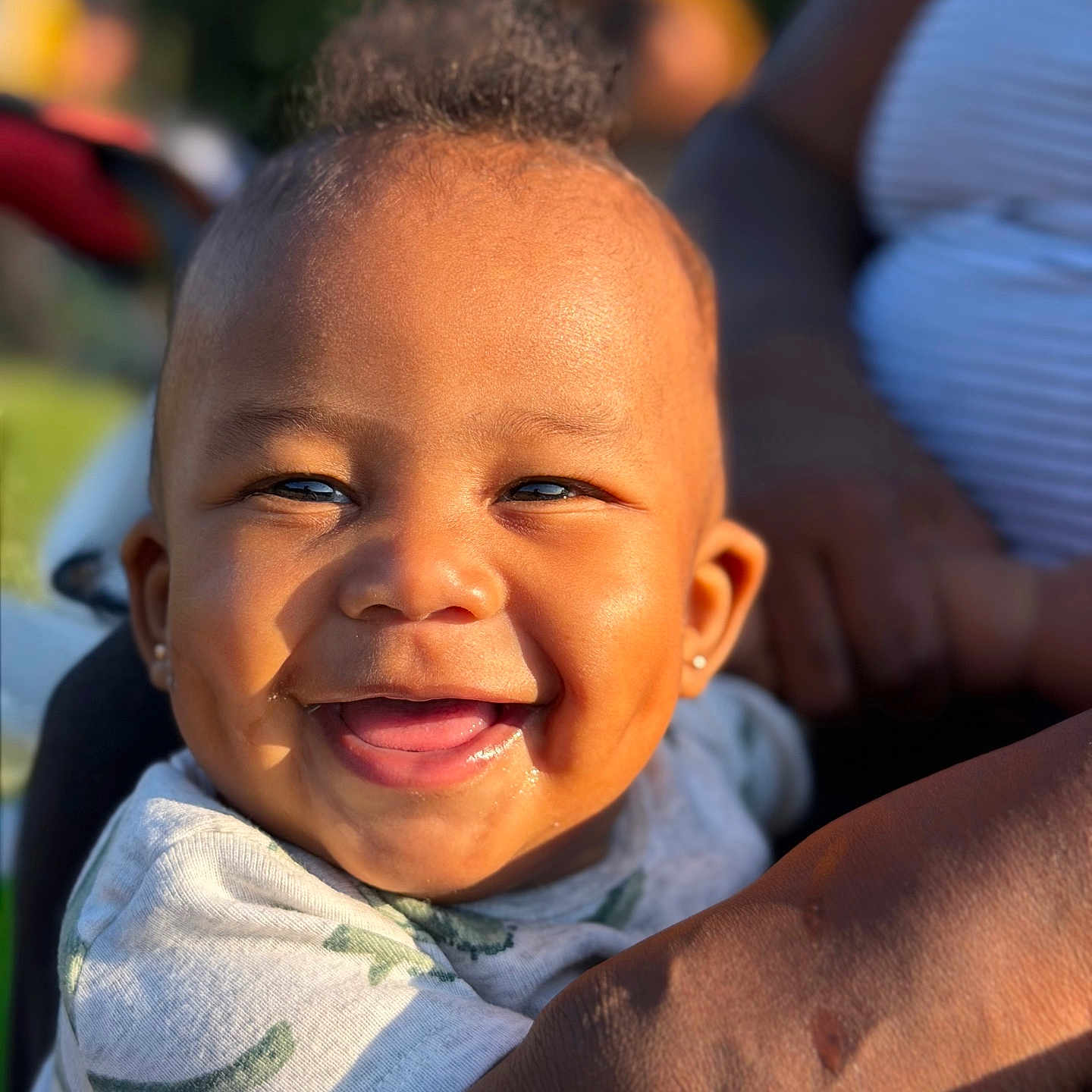 Ahlegend joined the competition — help win amazing prizes! adult, baby, child, close_up, clothing, earrings, eyes, face, hair, holding, infant, laughing, onesie, outdoor, parent, portrait, smiling, sunlight, teeth, topknot