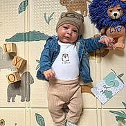 Lyo participe au concours pour gagner de l'argent avec cette photo : baby, child, infant, beanie, denim_jacket, plush_toy, wooden_blocks, play_mat, animal_print, cute, smiling, lying_down, sock, pants, white_onesie, indoor, colorful, toy, face, person