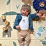 baby, child, infant, beanie, denim_jacket, plush_toy, wooden_blocks, play_mat, animal_print, cute, smiling, lying_down, sock, pants, white_onesie, indoor, colorful, toy, face, person