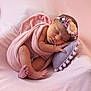 newborn, baby, sleeping, pink_blanket, floral_headband, pillow, pastel_colors, soft_texture, cozy, infant, wrapped, resting, peaceful, portrait, cute, small_feet, hand, face, closeup, indoors