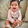 baby, child, clothing, couch, cozy, cute, face, hands, happy, indoor, infant, outfit, person, pigtails, pink, portrait, seated, shoes, smiling, socks