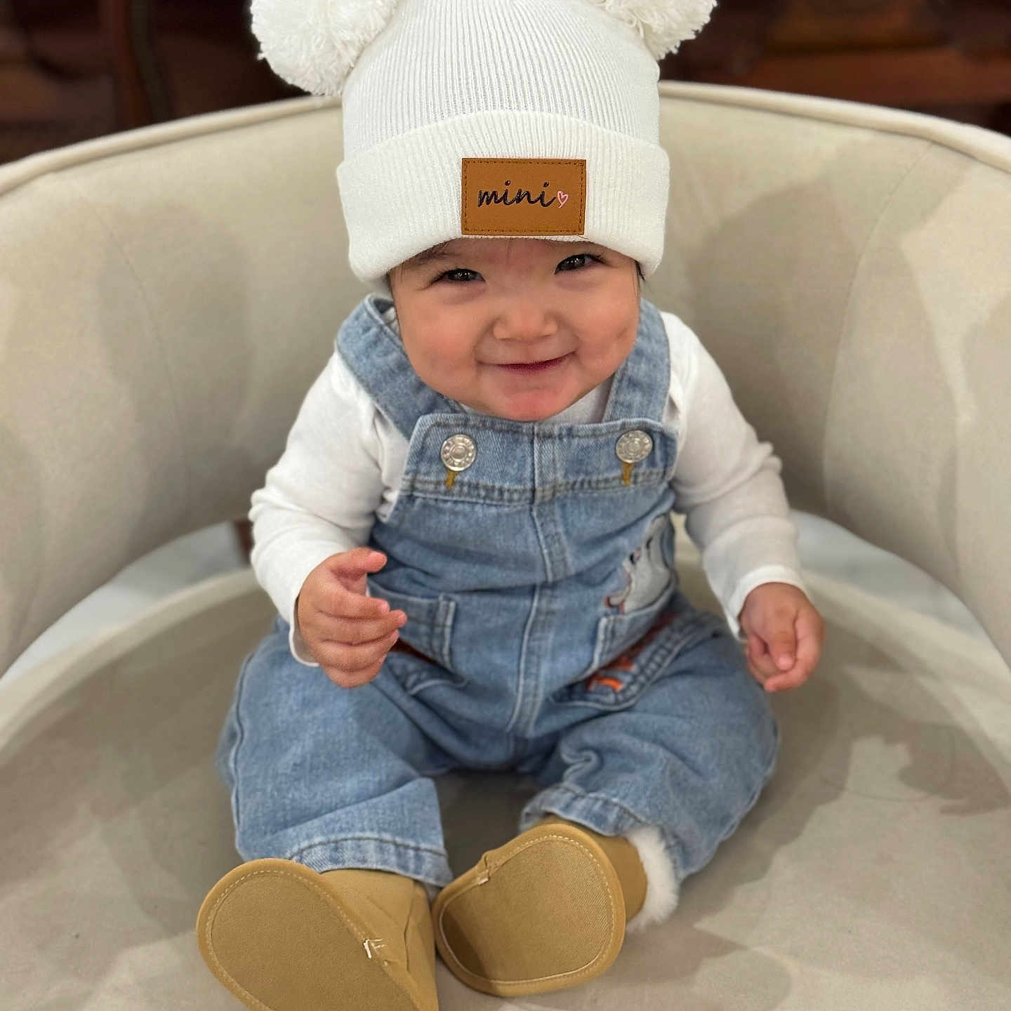 Alizeth is registered to the contest to win money with this photo: apparel, baby, boots, chair, child, clothing, comfortable, cute, denim_overalls, face, happy, hat, indoor, infant, person, pom_poms, portrait, sitting, smile, white_shirt