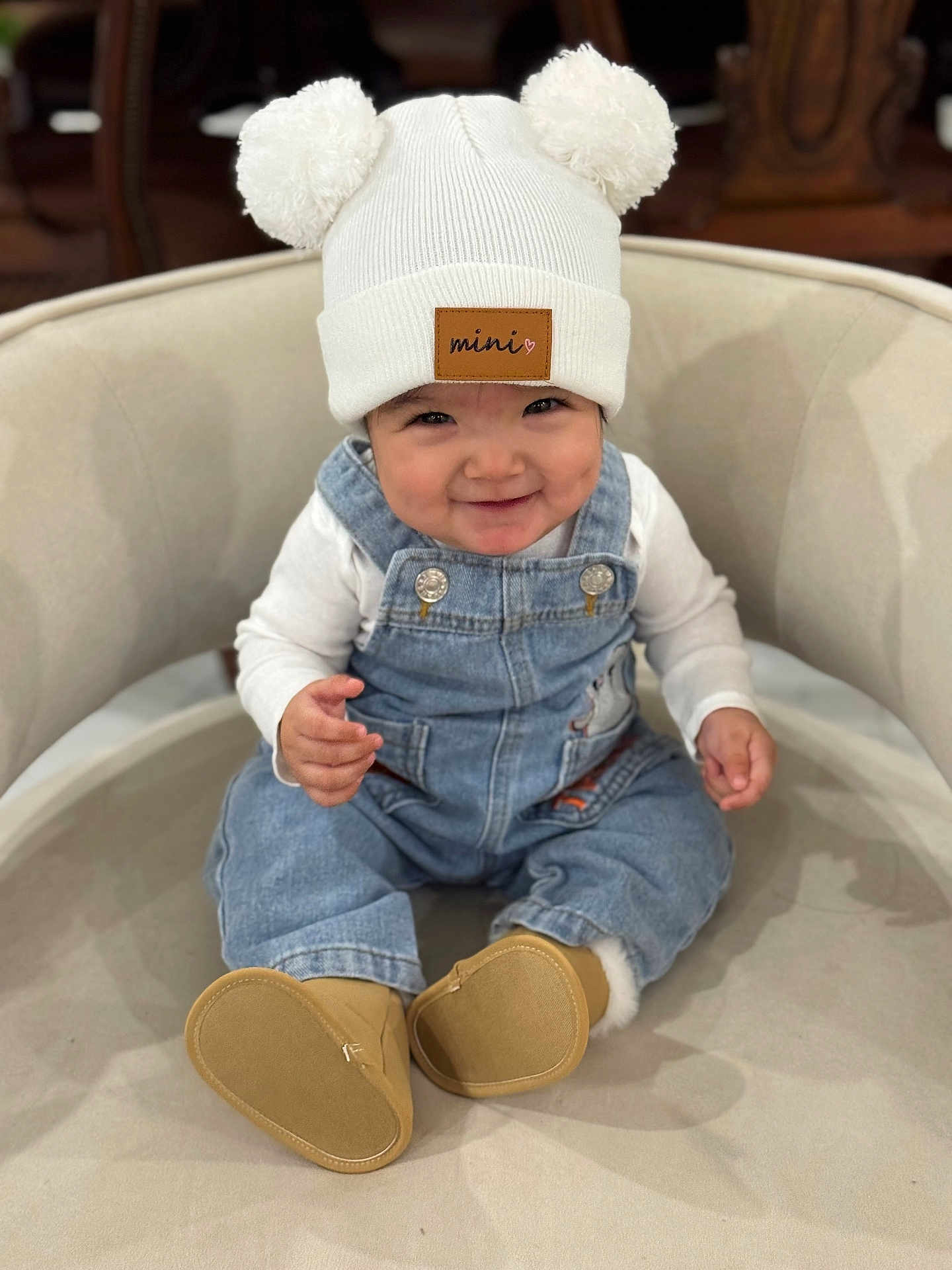 Alizeth is registered to the contest to win money with this photo: apparel, baby, boots, chair, child, clothing, comfortable, cute, denim_overalls, face, happy, hat, indoor, infant, person, pom_poms, portrait, sitting, smile, white_shirt