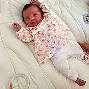Camille participe au concours pour gagner de l'argent avec cette photo : baby, bed, blanket, clothing, comfort, cute, foot, hand, heart_pattern, infant, lying_down, newborn, pajamas, person, rattle, skin, sleepwear, soft, toy, white