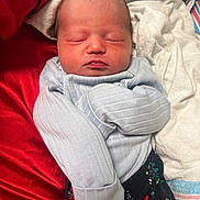 Elianna joined the competition — help win amazing prizes! newborn, baby, sleeping, infant, clothing, blanket, fabric, red, blue, patterned_pants, face, head, soft, cozy, resting, wrapped, human, skin, portrait, closeup