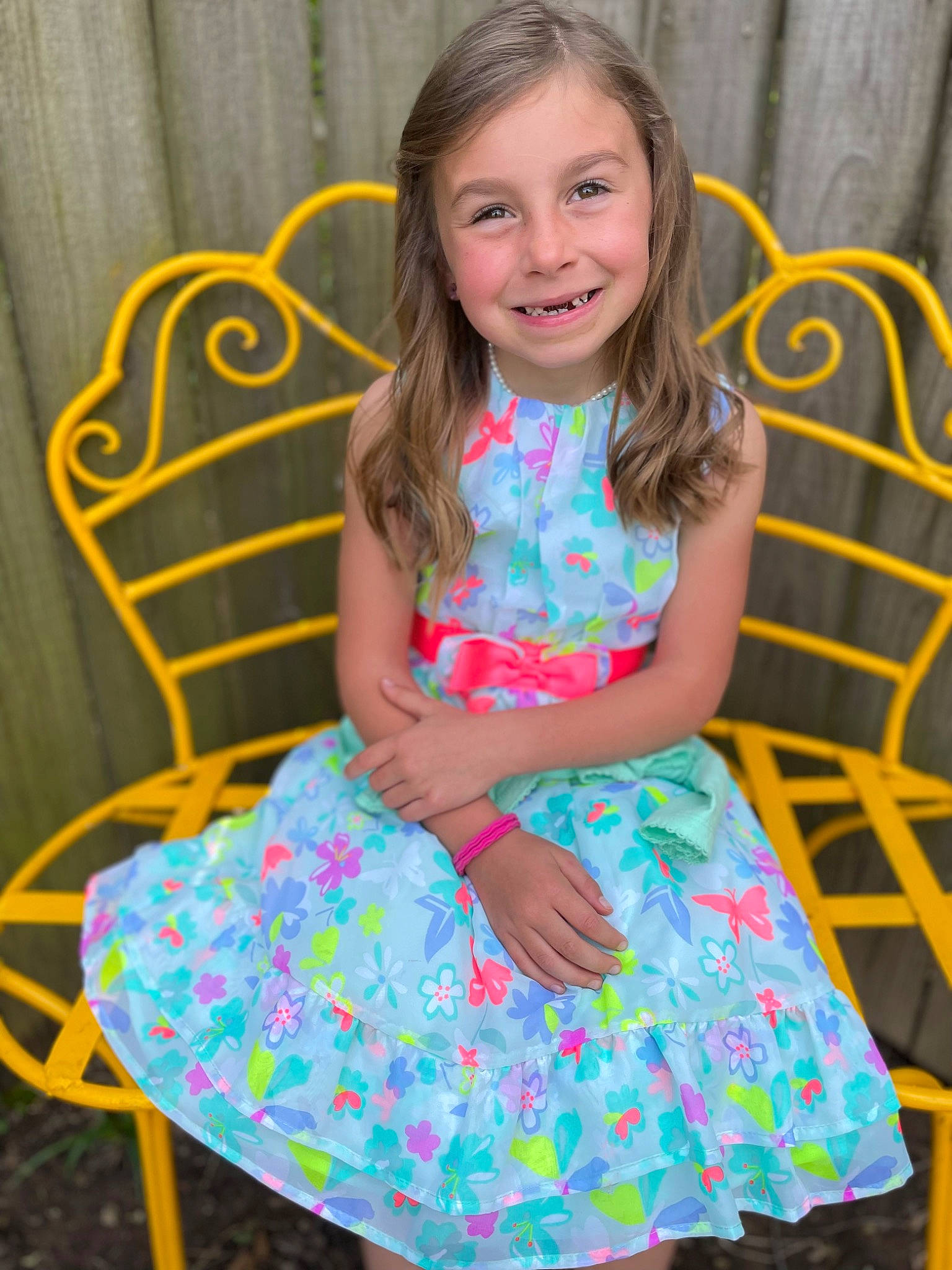 Sophi is registered to the contest to win money with this photo: arm, baby_toddler_clothing, chair, day_dress, dress, face, facial_expression, grass, hairstyle, happy, head, human_body, joy, leisure, one_piece_garment, person, pink, skin, sleeve, smile