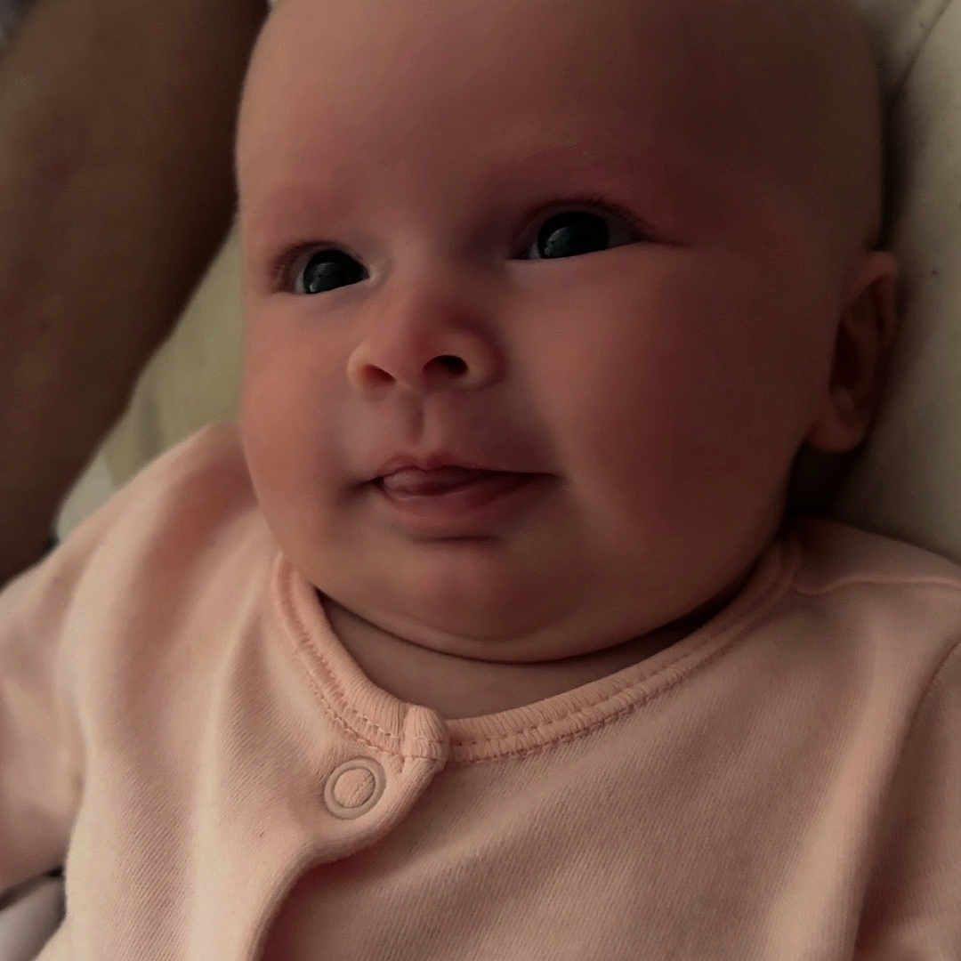 Gracie-Leigh is registered to the contest to win money with this photo: adult, baby, bed, bedding, blurred_background, cheeks, closeup, cute, expression, face, indoor, infant, onesie, person, pink_clothing, portrait, resting, skin, sleeping, tongue