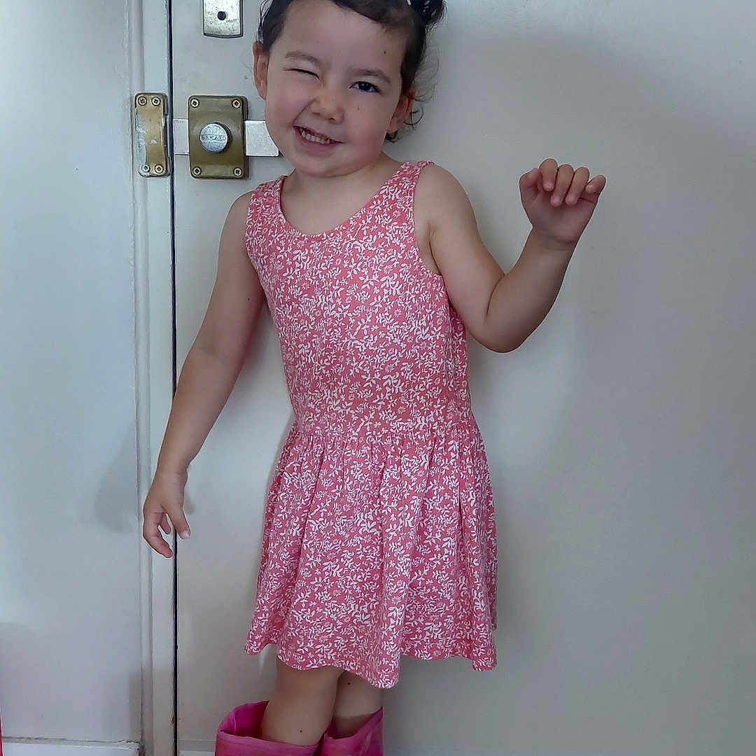 Selena a rejoint le concours — aidez-le/la à gagner de superbes lots ! casual, child, cute, door, fashion, flooring, girl, hair_clips, happy, indoors, person, pink_dress, playful, posing, rain_boots, smiling, standing, white_wall, winking, wooden_floor