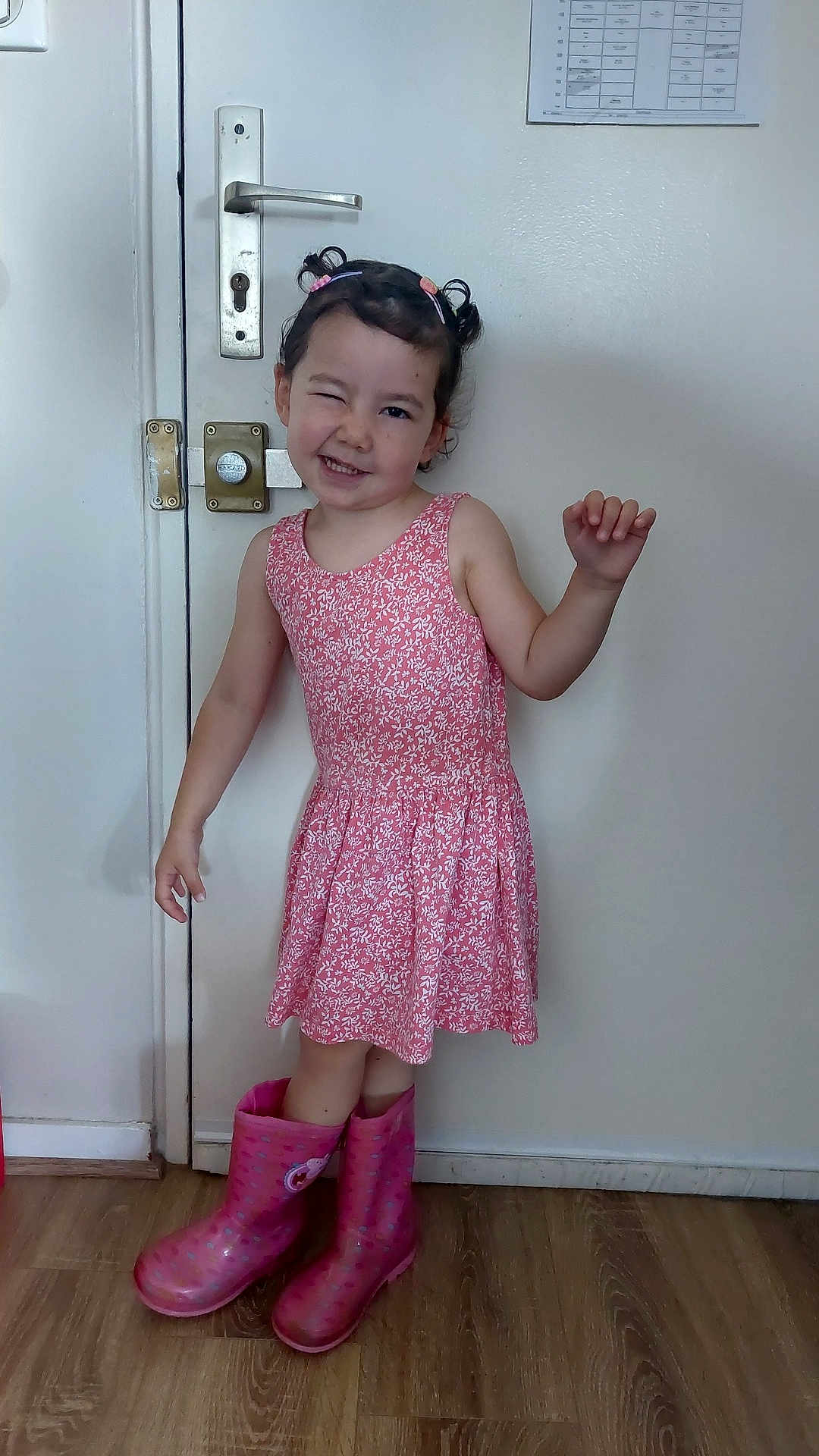 Selena a rejoint le concours — aidez-le/la à gagner de superbes lots ! child, girl, pink_dress, rain_boots, winking, smiling, standing, indoors, door, wooden_floor, hair_clips, playful, posing, white_wall, flooring, cute, person, fashion, happy, casual