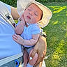 baby, infant, sun_hat, white_clothing, adult_hand, manicure, outdoor, green_grass, sunlight, garden, sleepy, cute, portrait, skin, person, holding, nature, summer, daylight, closeup