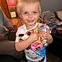 Lainey is registered to the contest to win money with this photo: toddler, child, smiling, blonde_hair, plush_toy, indoor, person, happy, clothing, hand, face, living_room, furniture, adult, wooden_door, pants, table, toy, cute, candid
