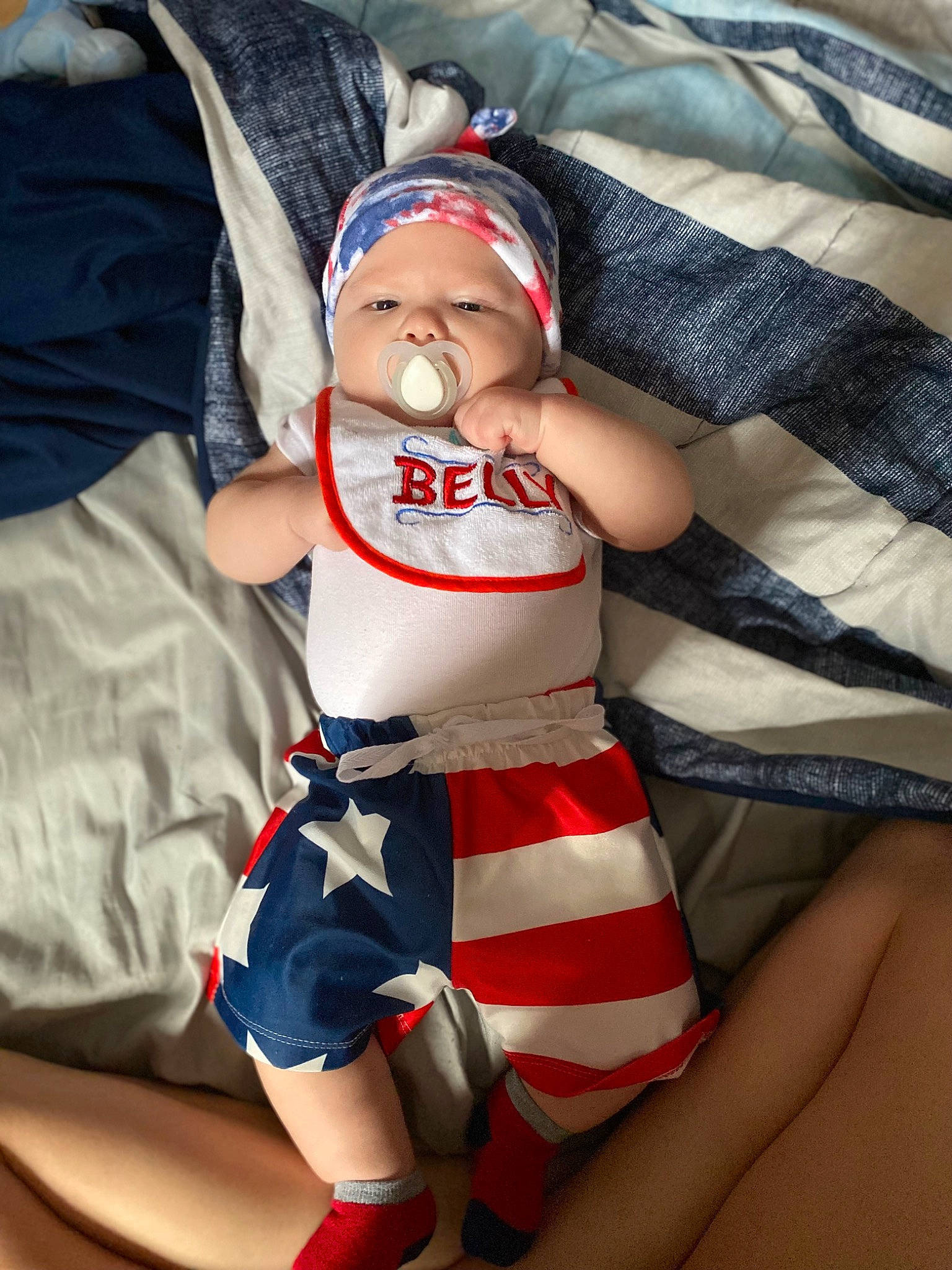 Ezekiel is registered to the contest to win money with this photo: abdomen, baby, baby_toddler_clothing, cap, comfort, elbow, finger, hat, headwear, human_body, human_leg, knee, lap, leg, person, sleeve, sock, textile, thigh, thumb