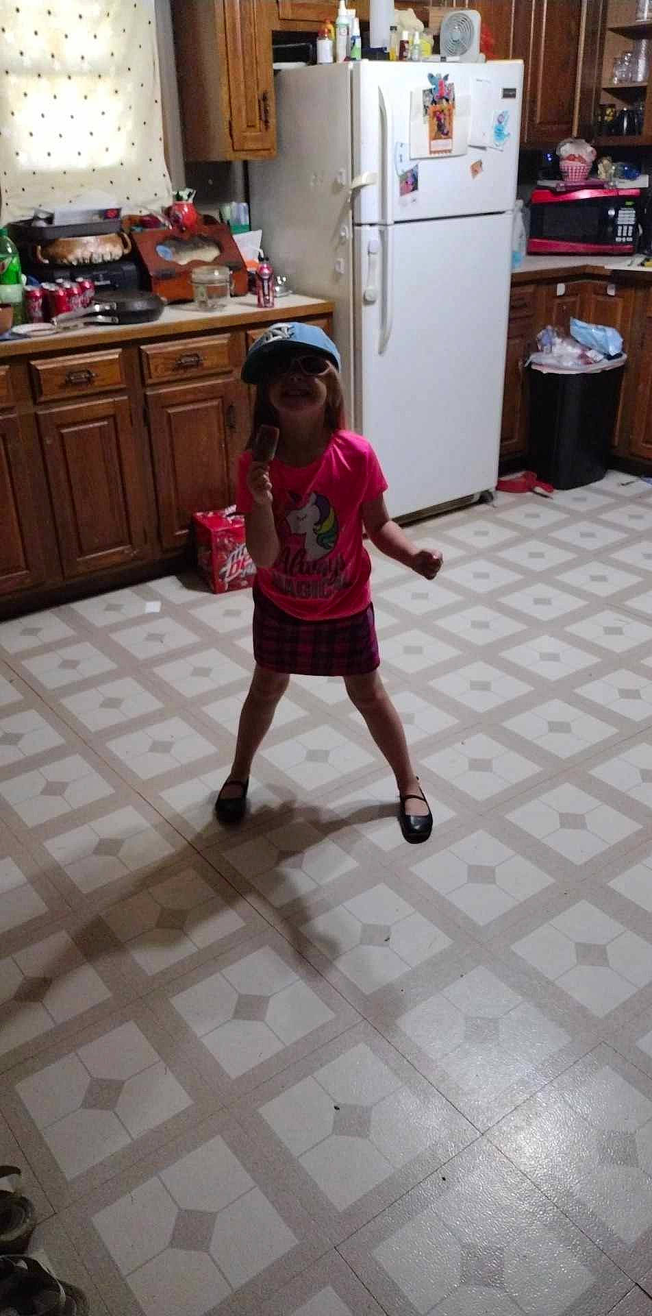 Korra is registered to the contest to win money with this photo: cabinetry, chest_of_drawers, child, cupboard, drawer, floor, flooring, hardwood, hat, home_appliance, human_leg, kitchen, kitchen_appliance, leg, major_appliance, person, refrigerator, shorts, standing, toddler