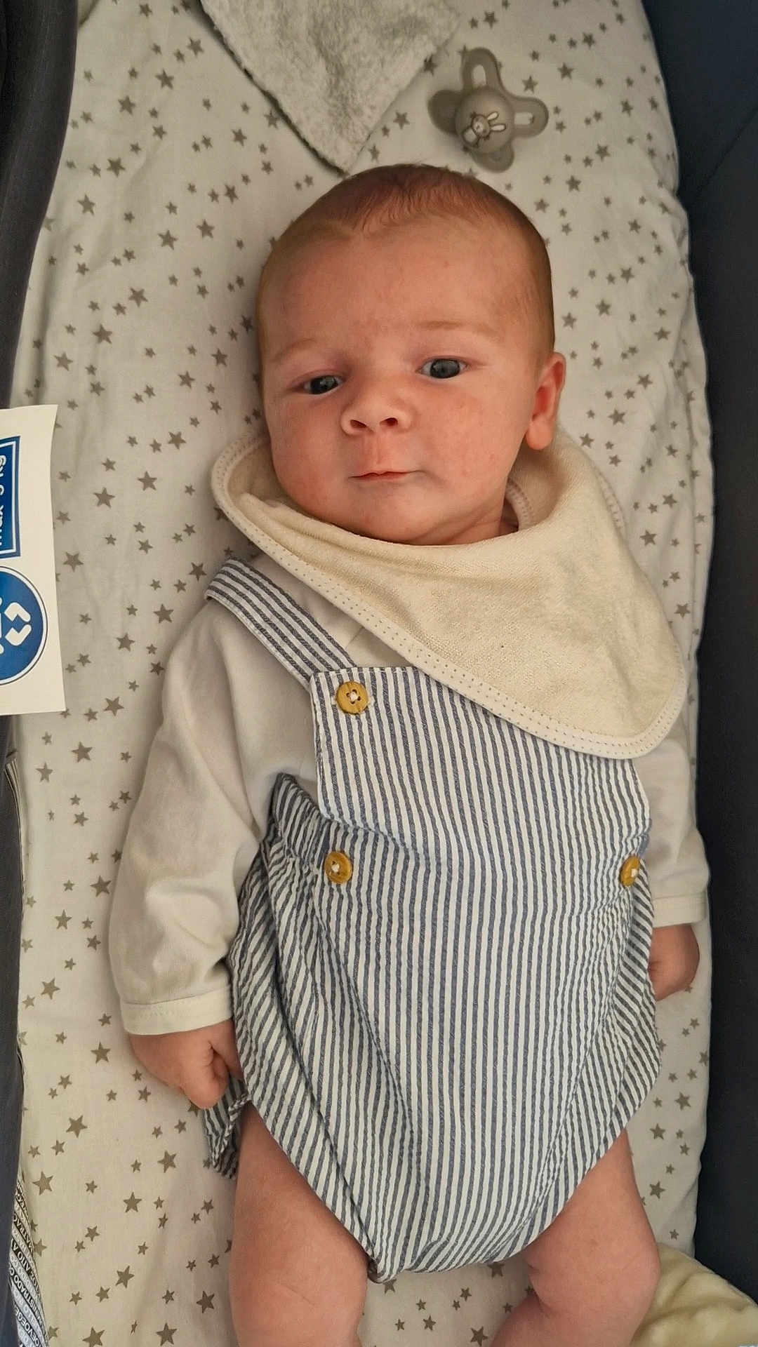 Noé participe au concours pour gagner de l'argent avec cette photo : baby, infant, pacifier, blanket, star_pattern, romper, bib, clothing, laying_down, indoor, cute, child, newborn, face, skin, hand, expression, soft_lighting, peaceful, portrait