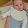 Noé participe au concours pour gagner de l'argent avec cette photo : baby, infant, child, person, arm, cushion, pillow, striped_clothing, bib, hand, face, skin, sitting, indoor, closeup, sleepwear, comfort, soft_texture, relaxing, cute