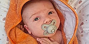 Noé participe au concours pour gagner de l'argent avec cette photo : baby, towel, pacifier, orange, wrapped, infant, cute, face, hand, pillow, pattern, bed, skin, eyes, comfort, newborn, lying_down, indoors, child, soft
