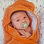 baby, towel, pacifier, orange, wrapped, infant, cute, face, hand, pillow, pattern, bed, skin, eyes, comfort, newborn, lying_down, indoors, child, soft
