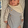 Noé participe au concours pour gagner de l'argent avec cette photo : baby, infant, lying_down, overalls, bib, socks, pacifier, mattress, star_pattern, blanket, cute, child, person, indoors, soft_toys, smiling, relaxed, clothing, newborn, sleeping_area