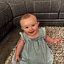 baby, blue_dress, carpet, child, couch, cozy, cute, floor, furniture, happy, indoor, infant, living_room, person, pillow, portrait, rug, sitting, smiling, young_child