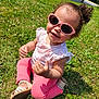child, toddler, grass, outdoor, sunlight, sunglasses, pink_clothing, curly_hair, smiling, sitting, summer, nature, footwear, cute, happy, playful, baby, greenery, casual, daylight