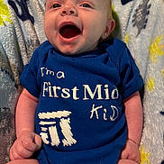 Kynxton joined the competition — help win amazing prizes! baby, infant, smiling, blue_onesie, text_on_clothing, blanket, happy, child, cute, face, mouth_open, lying_down, skin, hand, legs, indoors, soft_texture, patterned_blanket, young_child, portrait