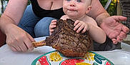 Dawson James joined the competition — help win amazing prizes! baby, child, curious, family, food, greenery, grilled_meat, happy, high_chair, meal, nature, outdoor, parent, picnic, plate, smiling, steak, summer, table, woman