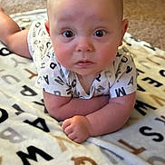 Jensen is registered to the contest to win money with this photo: alphabet, baby, blanket, carpet, child, clothing, curious, cute, expression, eyes, face, indoors, infant, letters, lying_down, person, portrait, short_sleeves, skin, toddler