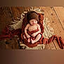 newborn, baby, sleeping, basket, knitted_hat, brown_blanket, wooden_floor, cozy, wrapped, infant, peaceful, soft_texture, indoors, portrait, sleep, child, warm_colors, cute, resting, blanket