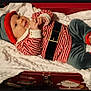 baby, infant, child, holiday_costume, elf_hat, striped_shirt, velvet_pants, blanket, red_box, smile, cute, indoors, portrait, holiday_theme, festive, soft_texture, feet, hands, happy, lying_down