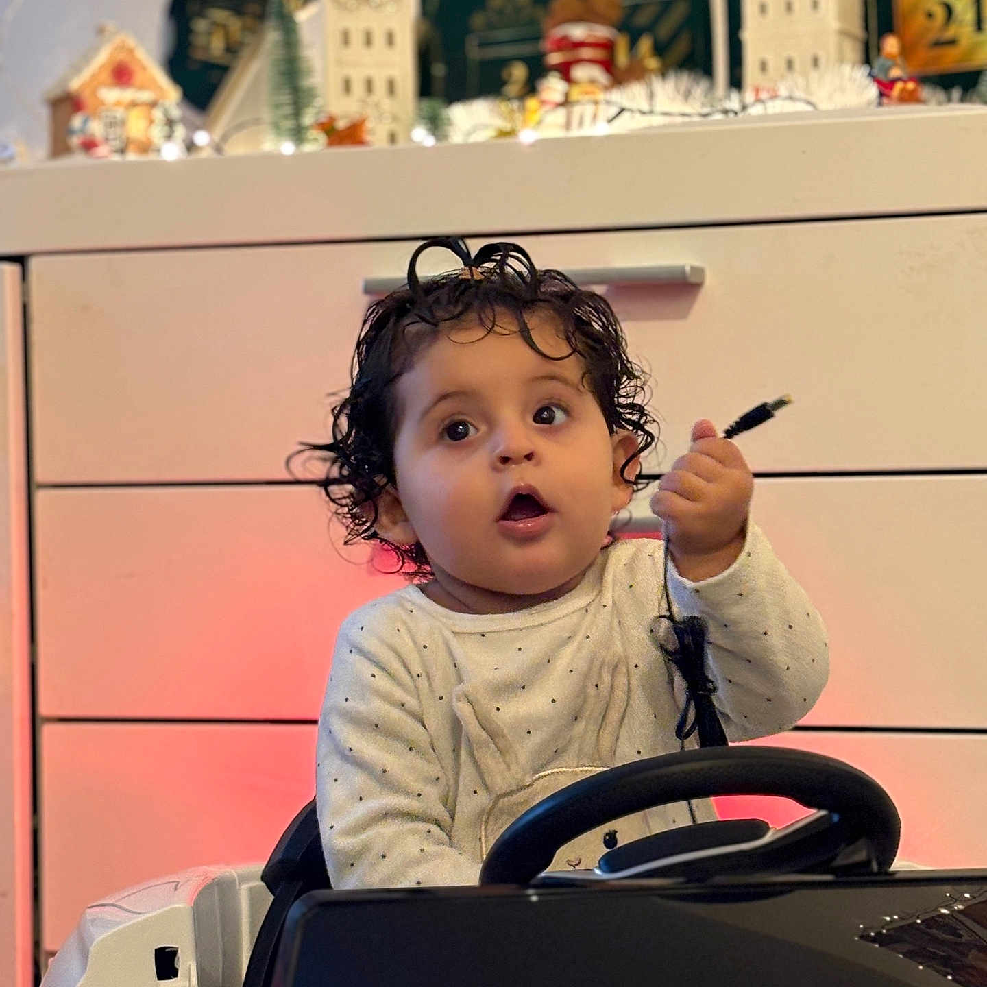 Dynna Authier a rejoint le concours — aidez-le/la à gagner de superbes lots ! baby, cable, child, christmas_village, curly_hair, dresser, festive_lights, hand, holiday_decor, indoor, mouth_open, onesie, polka_dots, portrait, seat, soft_lighting, steering_wheel, surprised_face, toddler, toy_car