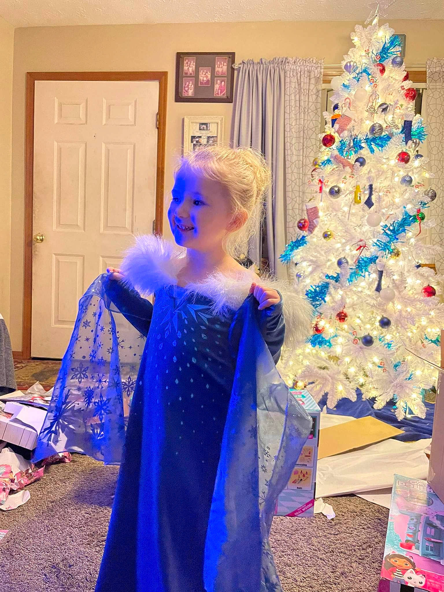 Lyra is registered to the contest to win money with this photo: blue, christmas_decoration, christmas_tree, costume_design, door, electric_blue, event, evergreen, fashion_design, formal_wear, fun, gown, holiday, joy, lighting, magenta, performing_arts, person, purple, toddler