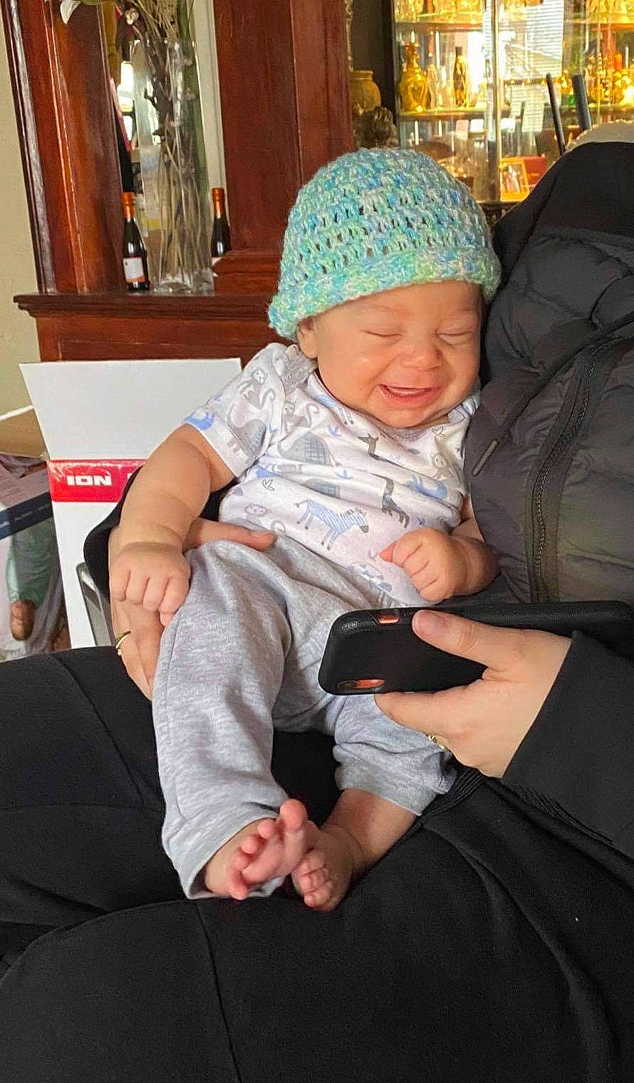 Mason is registered to the contest to win money with this photo: baby, baby_products, baby_toddler_clothing, cap, comfort, event, flooring, foot, fun, gesture, hand, happy, headwear, lap, person, picture_frame, sitting, skin, smile, thigh