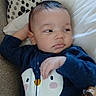 Elijah is registered to the contest to win money with this photo: baby, child, infant, onesie, penguin_design, couch, pillow, blanket, relaxed, indoors, cute, clothing, face, person, smiling, cozy, soft_fabric, pattern, hand, head
