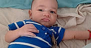 Elijah is registered to the contest to win money with this photo: baby, infant, blue_onesie, striped_clothing, bed, sheet, blue_sheet, lying_down, curious_expression, child, person, indoor, cute, small_hand, puckered_lips, casual, relaxed, skin, head, face