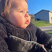 Lou a rejoint le concours — aidez-le/la à gagner de superbes lots ! child, toddler, baby, face, cheeks, blue_eyes, profile, side_view, sunlight, outdoors, blue_sky, house, building, stroller, jacket, fleece, winter_clothing, portrait, closeup, peaceful
