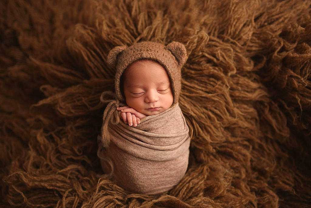Jovani is registered to the contest to win money with this photo: art, baby, cap, comfort, eye, grass, hand, happy, head, headgear, human_body, iris, knit_cap, linens, lip, person, toddler, tree, wood, wool