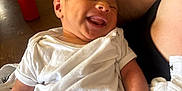 Jevonne is registered to the contest to win money with this photo: baby, newborn, smile, white_clothing, infant, arm, hand, indoor, table, candle, fruit_basket, wooden_chair, person, holding, happy, closeup, skin, relaxation, family, care