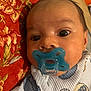 Jevonne is registered to the contest to win money with this photo: baby, pacifier, close_up, face, infant, child, onesie, pillow, patterned, red, blue, eyes, cute, cozy, indoor, portrait, sleepwear, young, head, skin