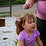 toddler, child, flower, hair_clip, purple_shirt, adult, outdoor, gravel, road, nature, greenery, person, expression, casual_clothing, short_sleeves, daylight, side_view, cute, happy, playing