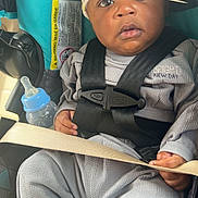 Kashe is registered to the contest to win money with this photo: baby, infant, car_seat, bottle, hat, clothing, straps, seatbelt, child, cute, indoors, portrait, person, baby_bottle, car, safety, expression, face, hands, cozy