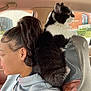 Socks is registered to the contest to win money with this photo: cat, person, car_interior, window, hoodie, black_and_white_cat, pet, side_profile, hair, earring, seat, upclose, domestic_animal, feline, looking_out, casual, daytime, animal_companion, relaxed, transportation