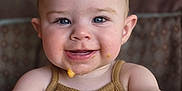 Gabriella is registered to the contest to win money with this photo: baby, blue_eyes, child, closeup, cute, face, food, hair, hand, happy, high_chair, indoor, infant, messy, mouth, portrait, skin, smiling, tank_top, young
