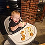toddler, child, high_chair, food, chicken_nuggets, french_fries, wrap, kitchen, brick_wall, stove, smiling, blue_eyes, indoor, table, sitting, person, meal, happy, home, cute