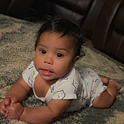 Aubriella is registered to the contest to win money with this photo: baby, infant, child, lying_down, carpet, onesie, cat_pattern, cute, indoors, portrait, face, hands, drool, soft_lighting, curious, young_child, skin, hair, eyes, expression