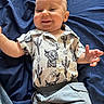 baby, child, smiling, shirt, cactus_pattern, short_sleeve, pants, blue_fabric, happy, face, skin, hand, infant, clothing, casual, lying_down, expression, cute, portrait, indoor